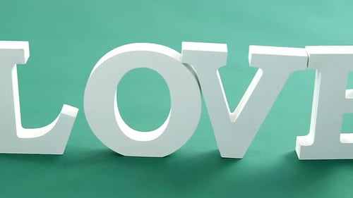 Gift box and alphabet love on green background