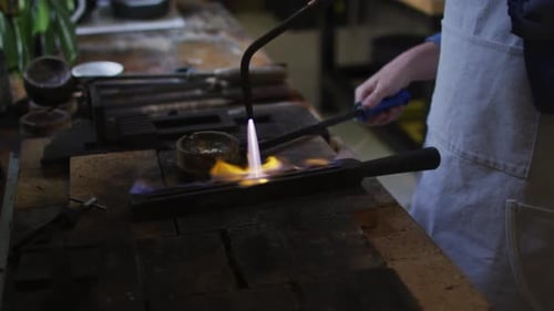 Mittelteil einer kaukasischen Juwelierin in Werkstatt mit Schürze, mit Gasbrenner