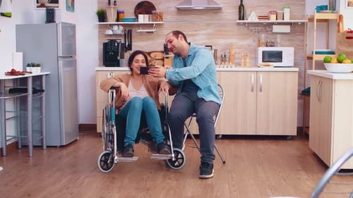 Couple Looks at Smartphone in Bright Kitchen