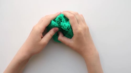 Hands Playing with Textured Slime with Bubbles Stretching the Gooey Substance on White Background