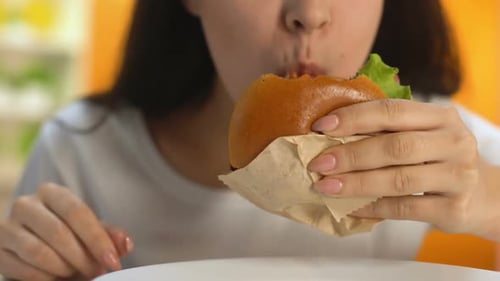 Young Adult Woman Eating Burger Close Up