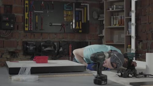 Man Assembling Furniture with Powered Screwdriver in Workshop