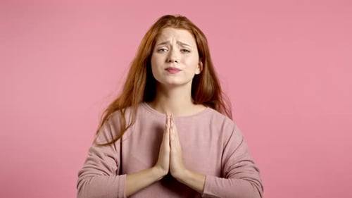 Young Woman Pleads with Hands Pressed Together