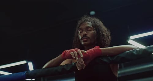 Sweaty Boxer Rests Against Ropes After Intense Training
