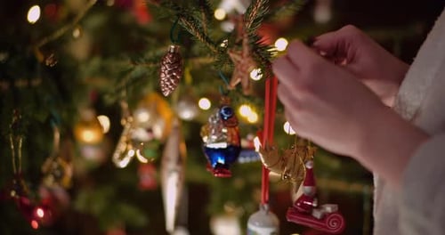 Person Decorating Christmas Tree with Festive Baubles