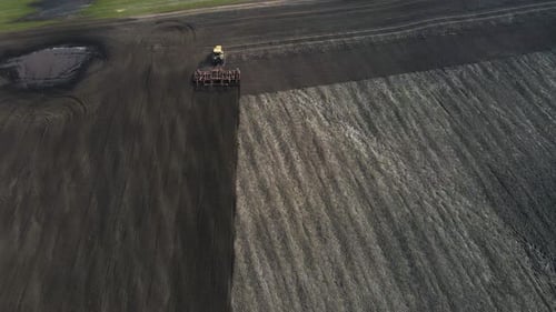 Aerial View of a Modern Yellow Tractor Plowing Dry Agricultural Field Preparing Land for Sowing