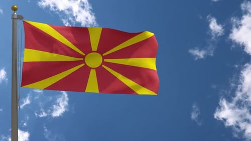 North Macedonian Flag Waving on Flagpole Against Blue Sky