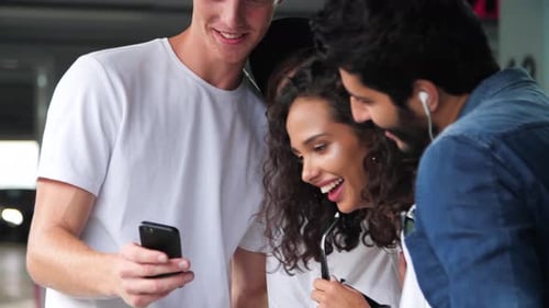 Happy Friends Using Mobile Phone At Parking Lot