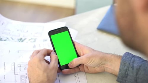 Man using smartphone, over the shoulder view