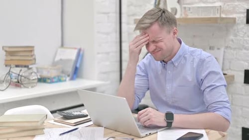 Man Typing on Laptop with a Headache