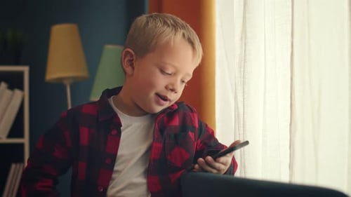 Boy Using Phone by Window in Home