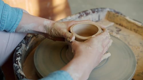 Potter shaping clay on a spinning wheel