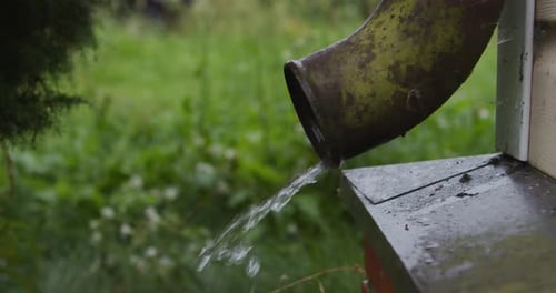 Water Flows from Green Metal Downspout onto Roof