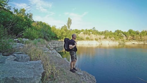 Man Standing on Cliff Edge Overlooking Lake