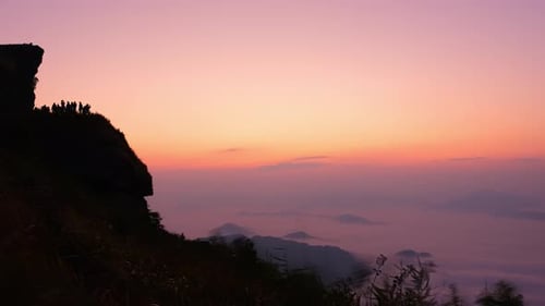 Mountainside Silhouette at Sunrise Over Foggy Landscape
