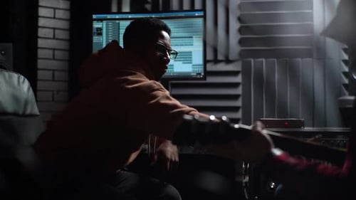 Side View of Talented Musician and AfroAmerican Producer Working Together on Track at Music Studio