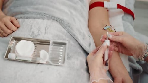 Nurse Taking a Blood Sample From a Patient Lying in a Hospital Ward