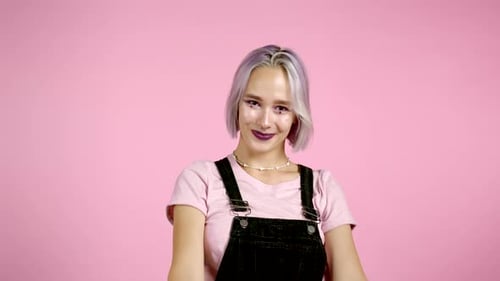 Confident Young Woman Giving Thumbs Up on Pink