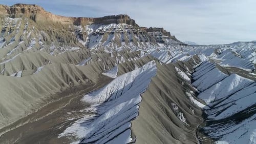 Flying over rugged desert landscape with snow on sand dunes