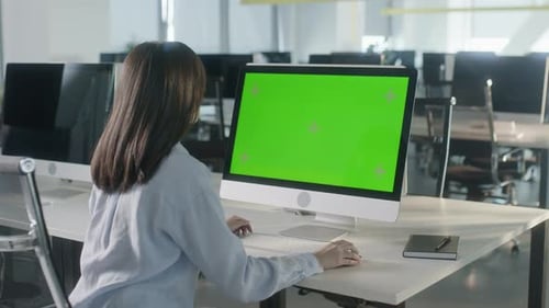 Business Multiethnic Woman Working on Desktop Computer with Green Screen Mock Up Display in Busy
