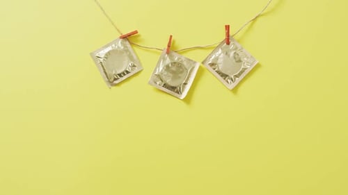 Video of close up of condoms hanging on green background