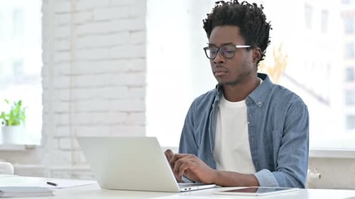 Man Typing on Laptop in Bright Office