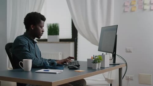 Man Working at Computer With Headphones at Home