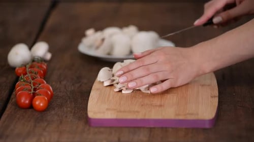 Person Slicing Fresh Mushrooms on Cutting Board