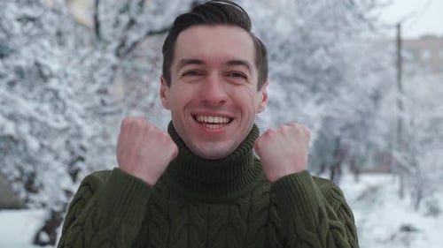 Excited man cheers in snowy outdoor setting