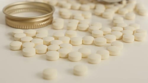 White Pills Scattered Near Bottle Cap on White Surface