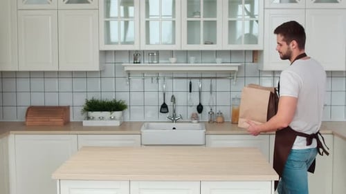 Man Brings Groceries to White Kitchen Counter