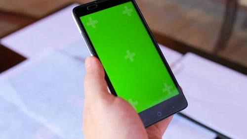 Construction engineer using a smartphone with a green screen looking for information on the internet