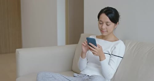 Woman Using Cellphone on Sofa at Home