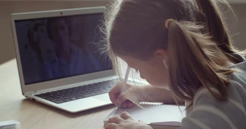 View From Behind Schoolgirl Child Sitting at Home in Quarantine Isolation, Looks at Laptop Screen