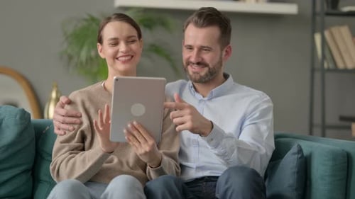 Smiling Couple Using Tablet at Home Together