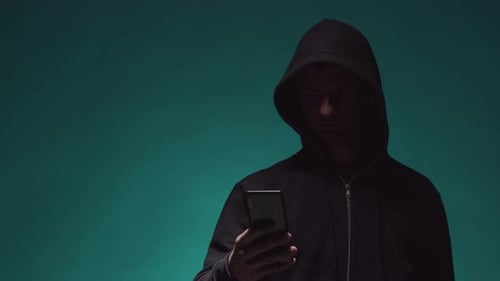 Mysterious Hooded Figure Using Mobile Device