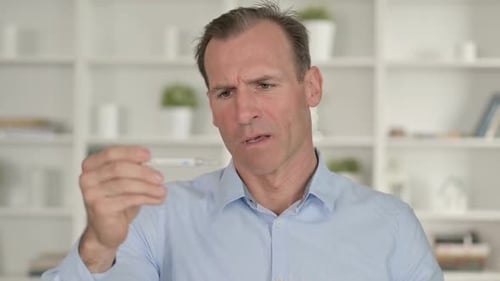 Retrato de hombre de negocios de mediana edad comprobando temperatura con termómetro