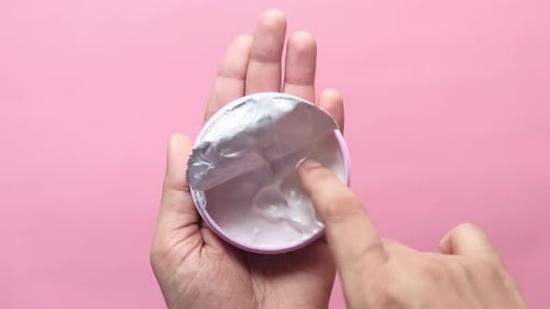 Woman Taking Cosmetic Cream From a Contianer, Top View