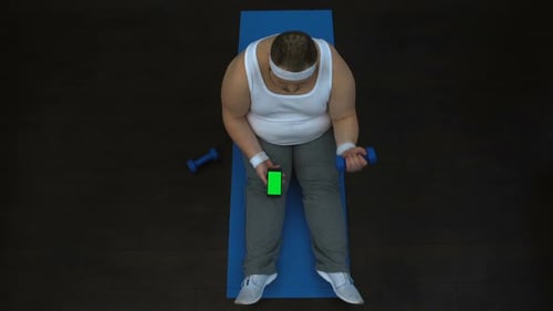 Adult Exercising with Dumbbell While Using Phone