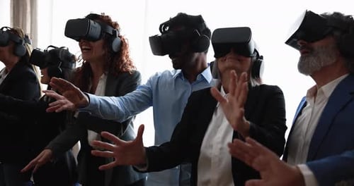Multiracial teamwork having fun wearing virtual reality headset inside coworking office