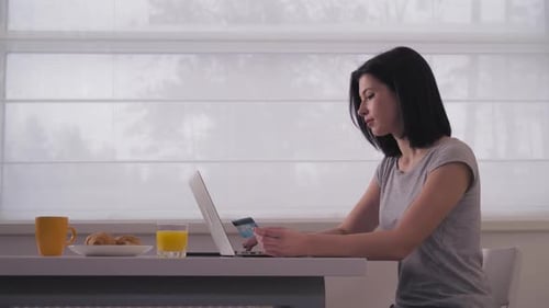 Woman Using Laptop and Credit Card at Home