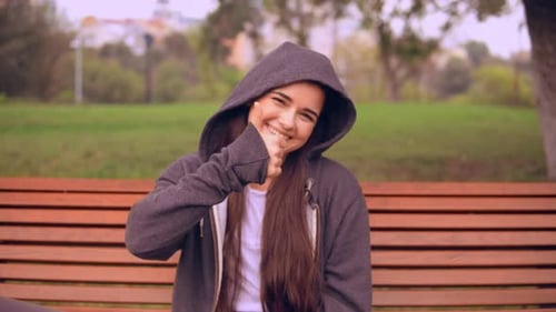 Smiling Woman Gives Thumbs Up on Park Bench