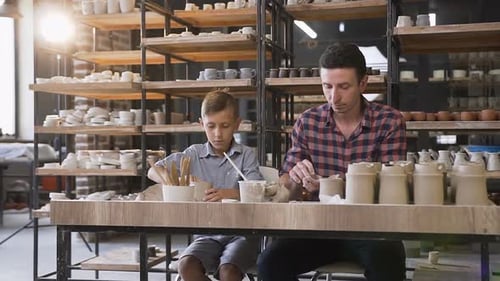Man and Boy Sculpting Pottery in Workshop