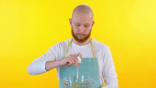 Man Cracking Egg into Glass Bowl