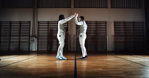 Two Men in Fencing Gear Duelling with Foils and Hi-Fiving After Battle