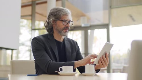 Man Uses Tablet in a Bright Workplace Setting