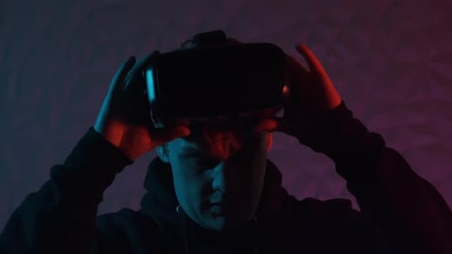 Man Takes Off VR Headset in Neon Lighting