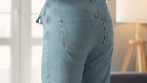 Young Woman Puts On Jeans Indoors