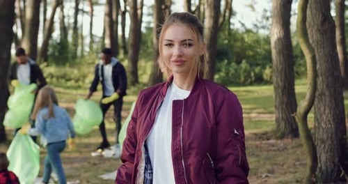 Woman Smiling as People Clean Up Forest Trash