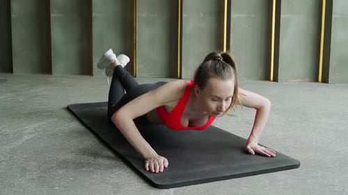 Woman Does Pushups From the Floor in the Gym